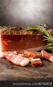 photo of delicious smoked ham on wooden table with rosemary