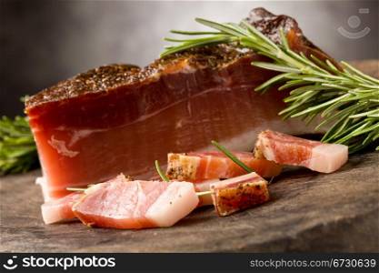 photo of delicious smoked ham on wooden table with rosemary