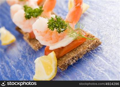 photo of delicious starter made of prawns and tomatoes on black bread