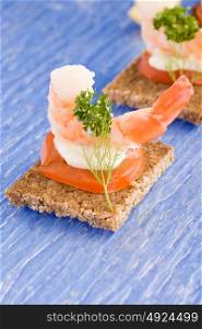 photo of delicious starter made of prawns and tomatoes on black bread