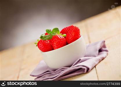 photo of delicious strawberries inside a bowl on wooden table