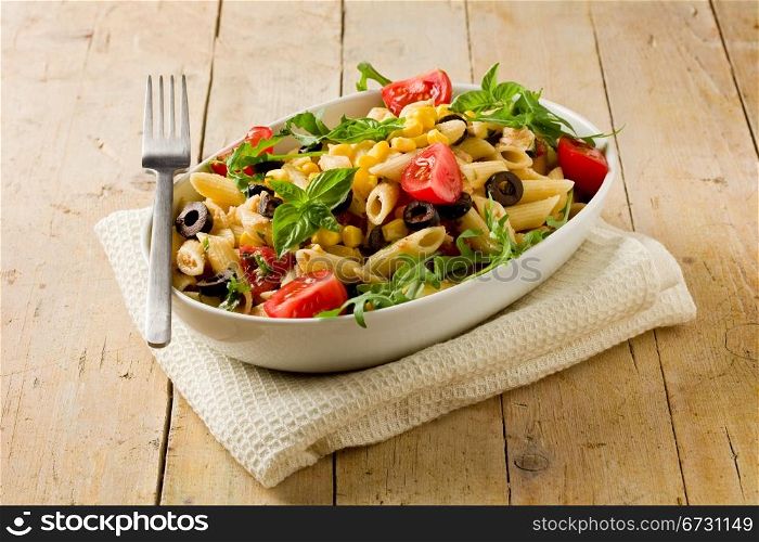 photo of delicious tasty pasta salad on wooden table with fresh vegetables
