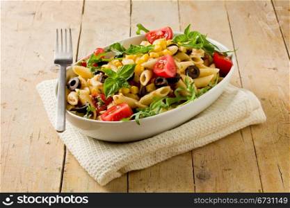 photo of delicious tasty pasta salad on wooden table with fresh vegetables