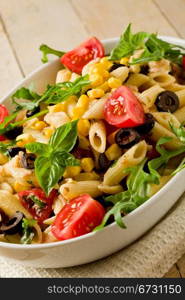 photo of delicious tasty pasta salad on wooden table with fresh vegetables