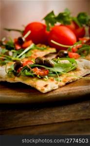 photo of delicious vegetarian pizza with arugula on wooden table