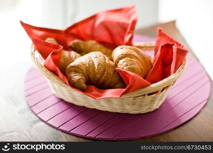 photo of delicious warm and fresh croissants on wooden table by daylight