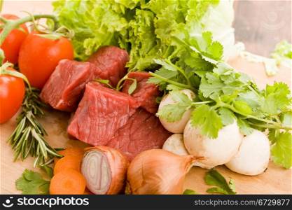 photo of diced raw meat with vegetables on a wooden chopping board