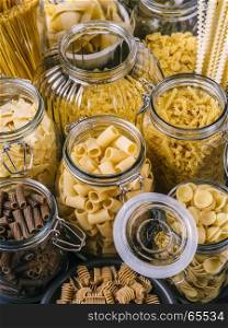 Photo of different pasta types in large glass jars.