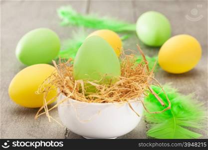 Photo of easter eggs and feathers over wooden table