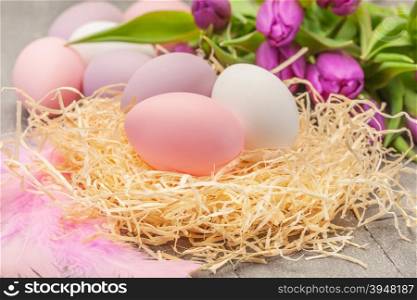 Photo of easter eggs and violet tulips over wooden table