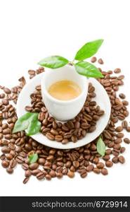 photo of espresso cup over coffee beans with green leaves on white isolated background