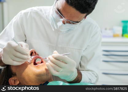 photo of european male dentist doing a checkup on a 40 years old man