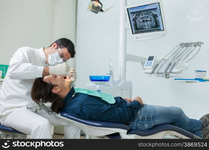 photo of european male dentist doing a checkup on a 40 years old man