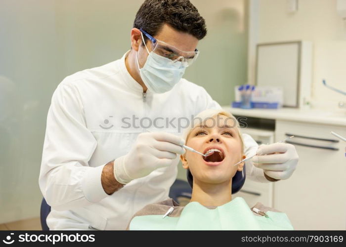 photo of european male dentist doing a checkup on a blonde female patient
