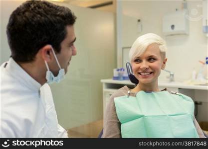 photo of european male dentist speaking with his blonde female patient