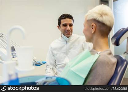 photo of european male dentist speaking with his blonde female patient