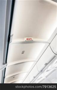 Photo of exit sign on ceiling on aircraft with lights