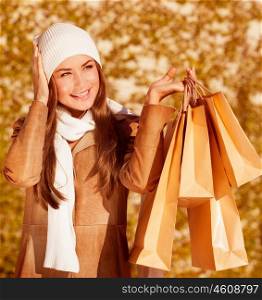 Photo of fashionable woman hold golden presents bag on yellow autumnal background, closeup portrait of cute stylish girl having fun outdoors, autumn seasonal sale, spend money concept &#xA;