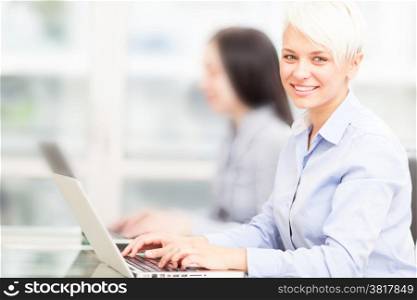photo of female blonde employee working on her computer in office
