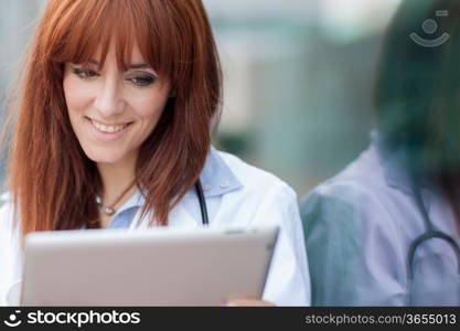 Photo of female doctor with tablet pc standing next to glass wall