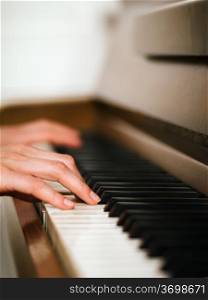 Photo of female hands playing an upright piano. Very shallow depth of field with focus on fingers.&#xA;