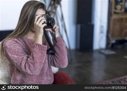 photo of Female photographer with photo camera at home sitting on the sofa