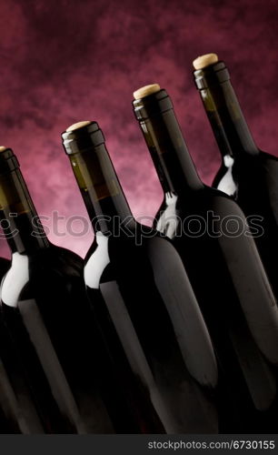 photo of five wine bottles in front of violet background