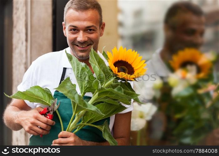 Photo of florist with a sunflower in his hands next to his shop