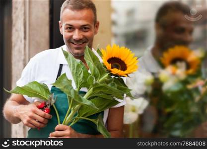 Photo of florist with a sunflower in his hands next to his shop