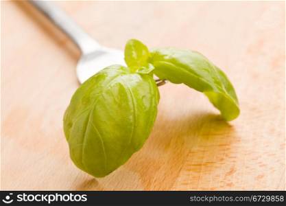 photo of fork with basil leaves on wooden table