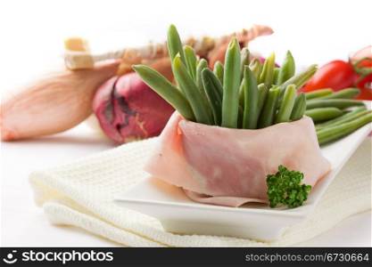 photo of french beans with wrapped ham on white background