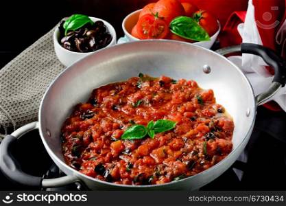 photo of fresh cooked tomato sauce with olives and basil