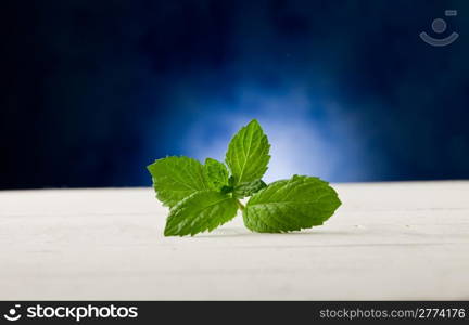 photo of fresh mint leaves on wooden table highlighted by spot light