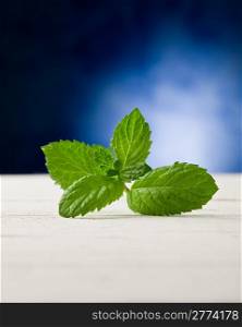 photo of fresh mint leaves on wooden table highlighted by spot light