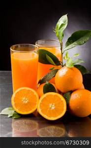 photo of fresh orange juice with water drops and green leaves