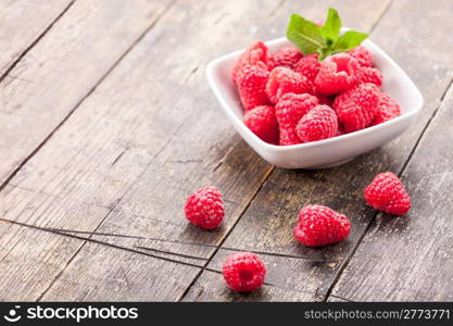 photo of fresh raspberries inside a bowl with mint on wooden table