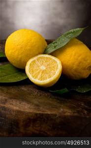 photo of fresh yellow lemons with leaves and water drops on wooden table