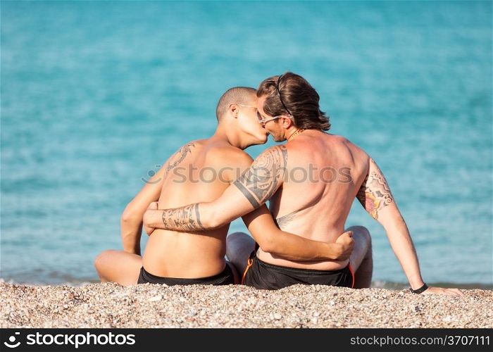 Photo of gay couple kissing in front of the beach