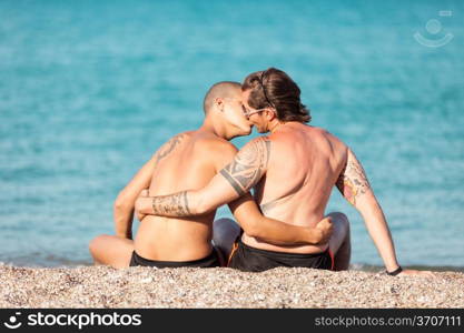 Photo of gay couple kissing in front of the beach