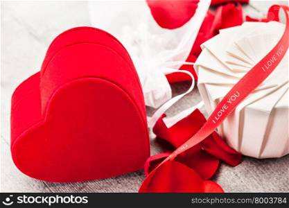 Photo of gift box, red roses and petals over wooden table