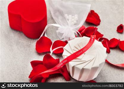Photo of gift box, red roses and petals over wooden table
