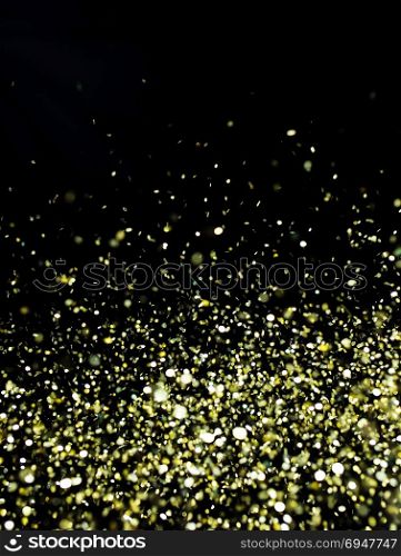 Photo of golden glitter on a black background. Golden explosion of confetti. Holiday background. Photo of golden glitter on a black background. Golden explosion