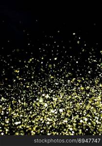 Photo of golden glitter on a black background. Golden explosion of confetti. Holiday background. Photo of golden glitter on a black background. Golden explosion