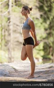Photo of gorgeous blonde woman doing stretching exercises while standing on the rock