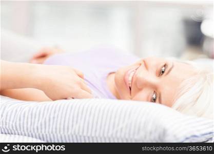 Photo of gorgeous blonde woman posing on the bed while smiling