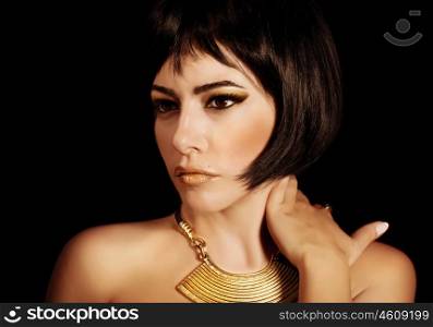 Photo of gorgeous woman with Cleopatras makeup, closeup portrait of beautiful female with stylish haircut isolated on black background, young lady wearing fashionable golden necklace, beauty salon