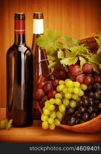 Photo of grape wine still life, two bottle of vine and basket with different kind of grapes on wooden table, alcohol beverage, fresh juicy fruits, winery restaurant, harvest season, luxury concept