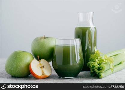 Photo of green smoothie with cerely and apple in two glass containers on white background. Healthy organic juice. Dieting concept.
