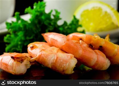 photo of grilled king prawns on black glass table with reflection