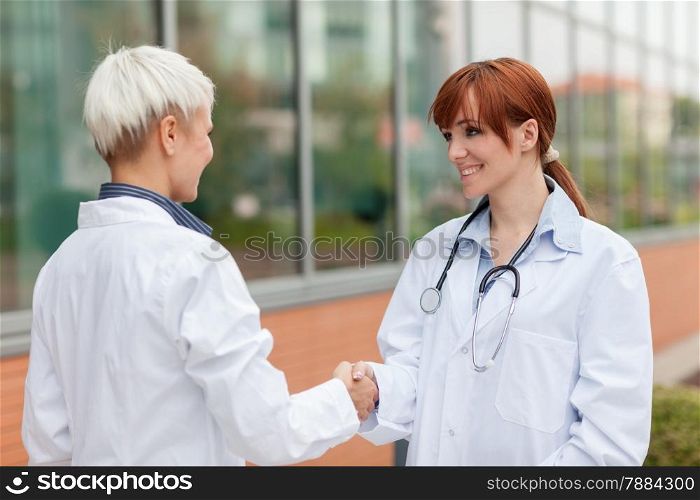 Photo of handshake between two female doctors standing outdoor